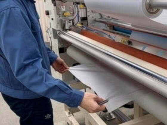 ラミネーターに通してフィルムを貼っている用紙